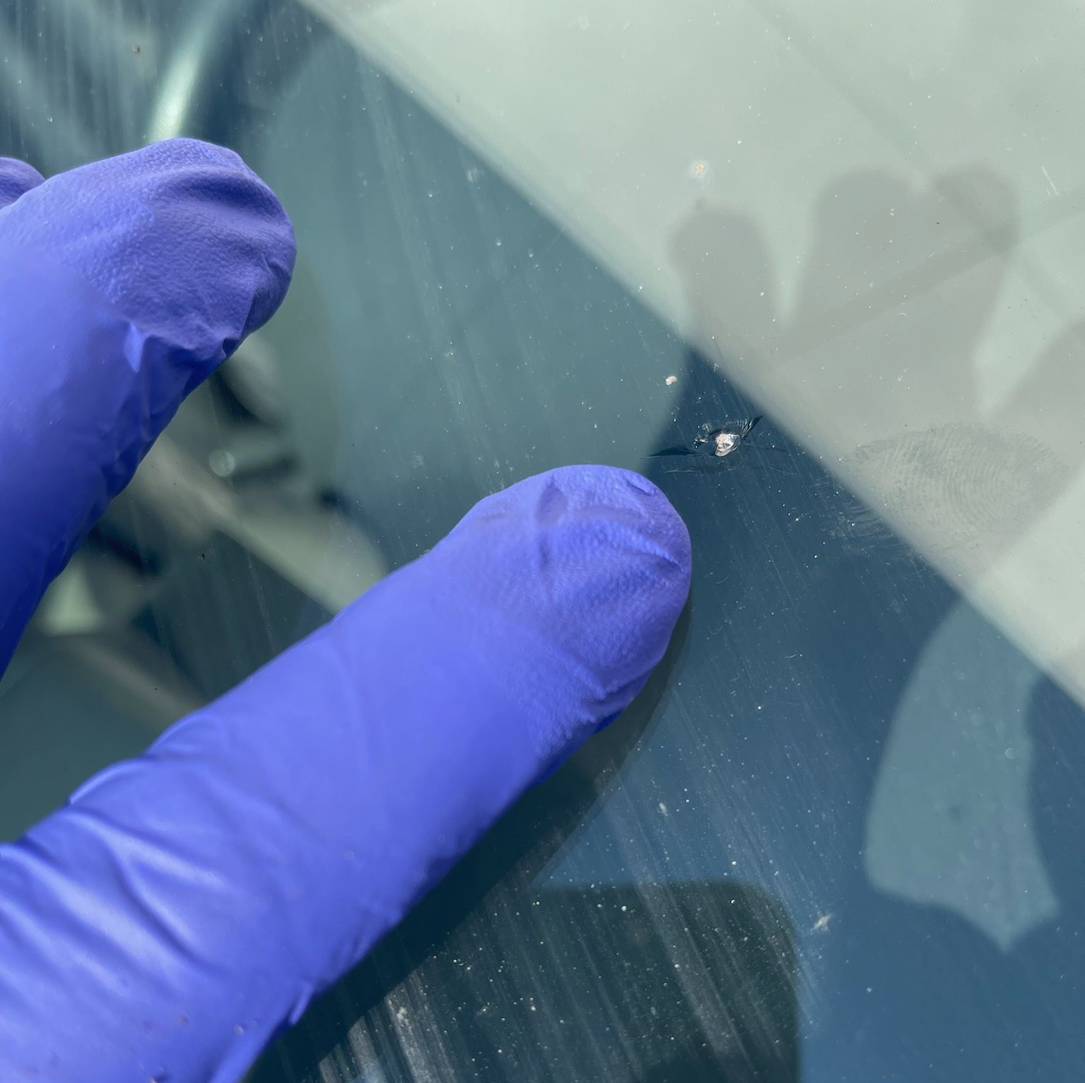 A person is performing a chip repair on the front windshield of a vehicle