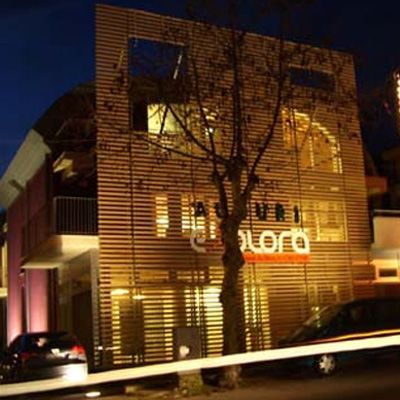 Facciata di un edificio di notte con listelli di legno orizzontali. Un grande cartello recita 