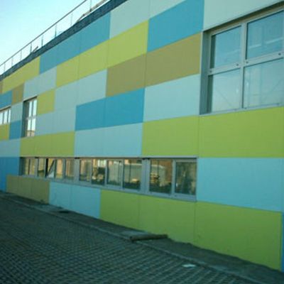 Facciata colorata dell'edificio con grandi pannelli rettangolari blu, gialli e beige e finestre.