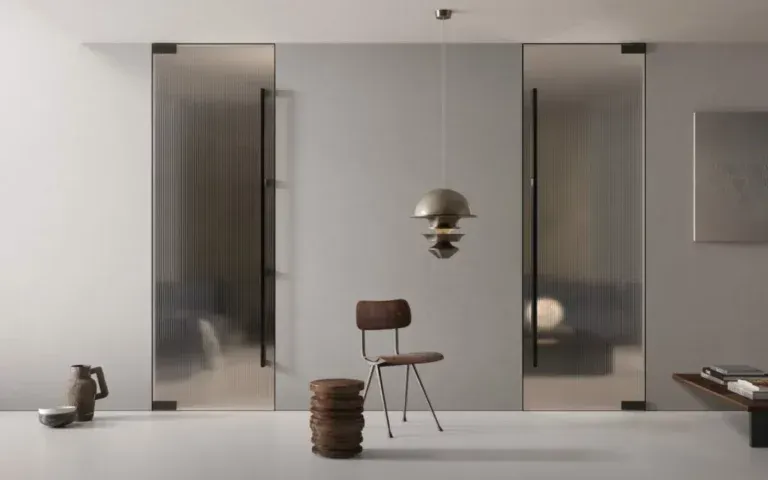 Interno moderno con porte scorrevoli in vetro smerigliato. Una sedia e uno sgabello sono posizionati di fronte a una parete centrale con una lampada a sospensione.