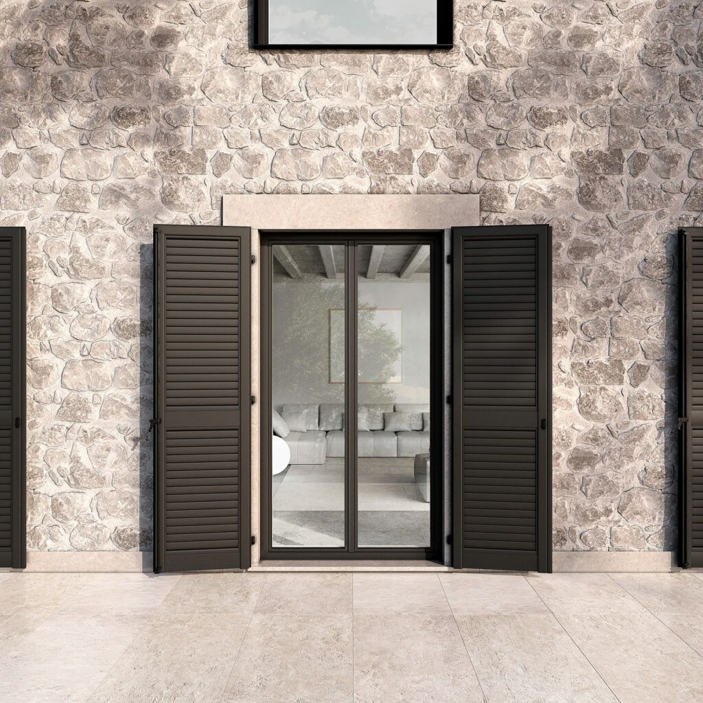 Vista esterna di un edificio con facciata in pietra. Una porta a vetri doppia con persiane scure su entrambi i lati.