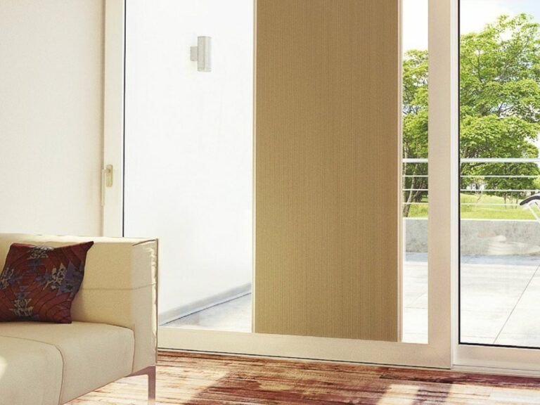 Vista interna di uno spazio abitativo con una porta scorrevole che si apre su un patio. Un pannello verticale color cuoio copre una parte della porta.