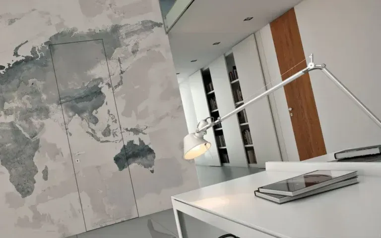 Interno di un ufficio con un murale raffigurante una mappa del mondo, una scrivania con telefono e lampada e scaffali incorporati.