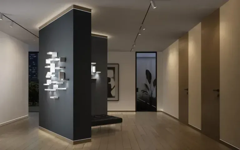 L'interno di una galleria d'arte è caratterizzato da pareti grigio scuro e beige chiaro, una panca nera e un'illuminazione artistica moderna.