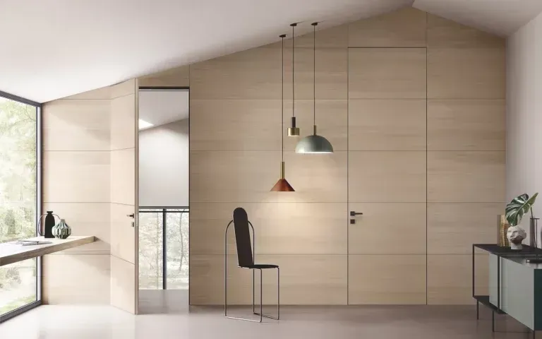 Camera moderna e luminosa, con pareti rivestite in legno, porte nascoste e arredamento minimalista. Tra i dettagli figurano lampade a sospensione, una sedia e un'ampia finestra.