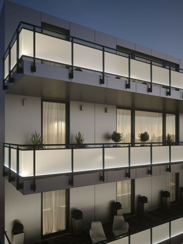 Esterno di un edificio moderno al tramonto, con balconi illuminati in vetro smerigliato, piante in vaso e mobili da esterno.