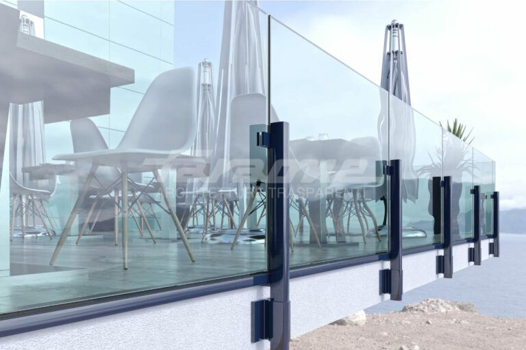 Ringhiera in vetro su un ponte con tavoli, sedie e ombrelloni, probabilmente in un ristorante all'aperto con vista sull'oceano.