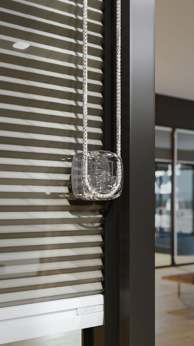 Una piccola borsa argentata appesa a una trave scura verticale davanti a una tenda a strisce.