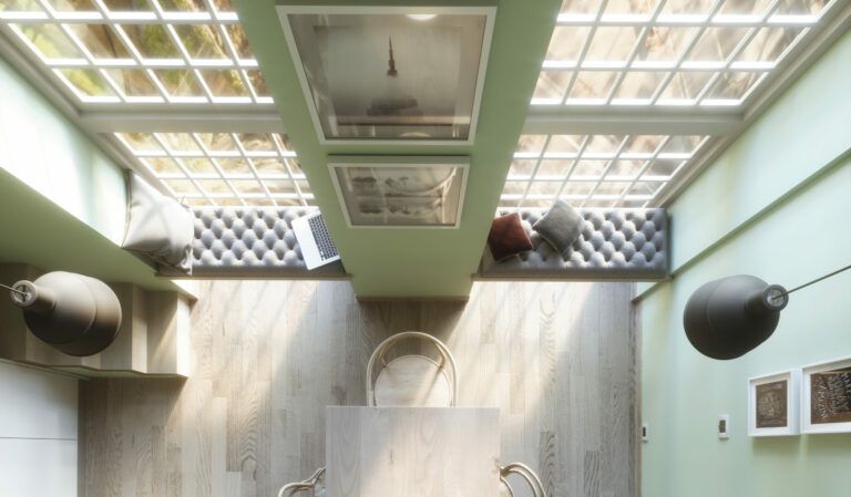 Vista dall'alto di una moderna sala da pranzo con soffitto in vetro. Pareti verde oliva circondano un tavolo in legno e lampade circolari sospese.