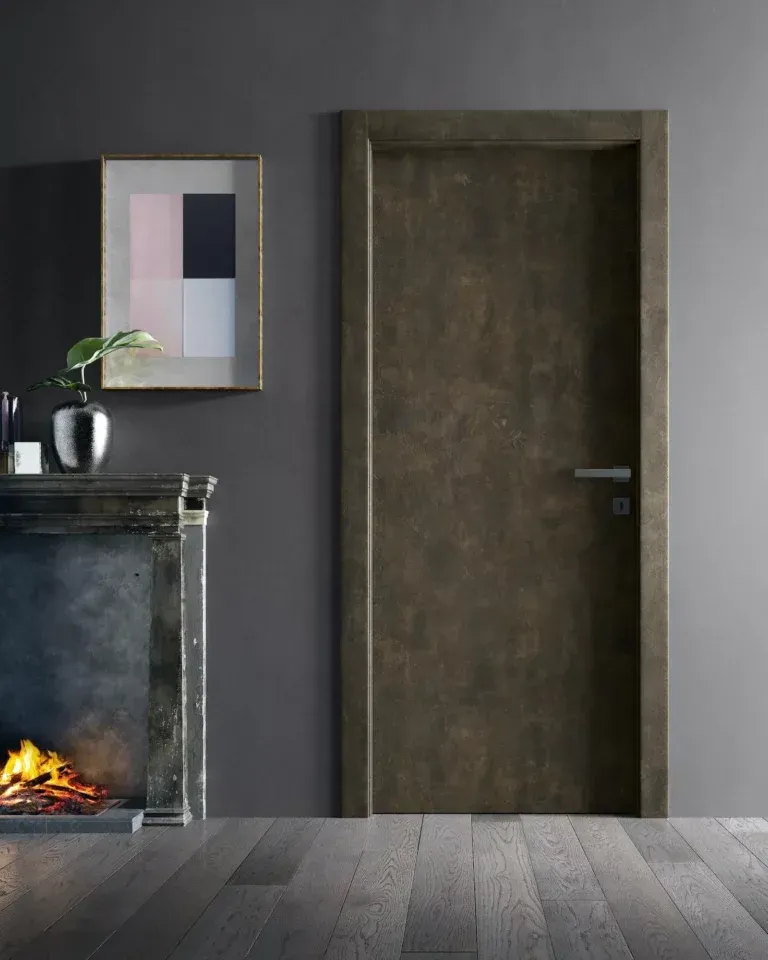Una porta di legno scuro in una stanza grigia. Si intravede un camino con il fuoco acceso, insieme a opere d'arte e decorazioni.