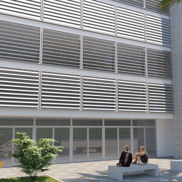 Esterno di un edificio moderno con finestre a stecche orizzontali e porte in vetro, due figure sedute su una panchina.