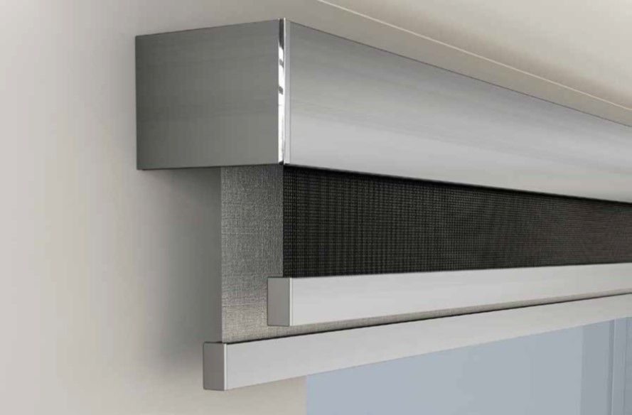 Primo piano di una moderna tenda per finestre con cornice argentata e tenda a rete grigio scuro che copre parzialmente una finestra.