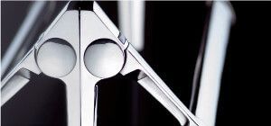 Primo piano di un oggetto d'argento con un disegno geometrico e due aperture circolari. Lo sfondo è nero.