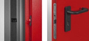 Primo piano di una porta rossa con maniglia e serratura nere e un chiavistello su uno stipite della porta abbinato.