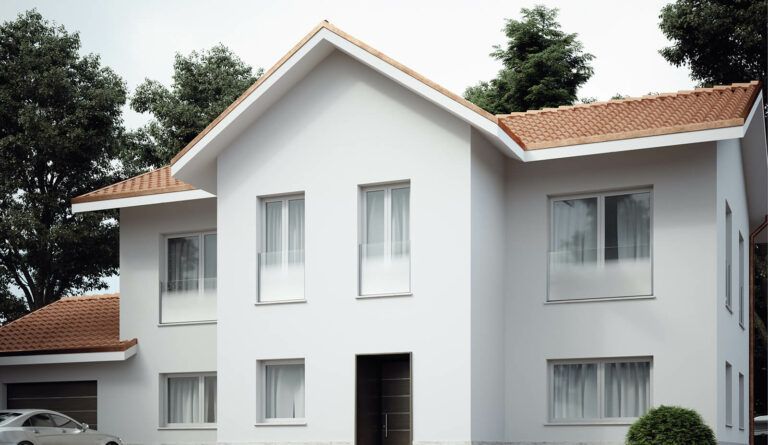 Casa bianca a due piani con tetto di tegole rosse e alberi sullo sfondo. La porta d'ingresso è nera.