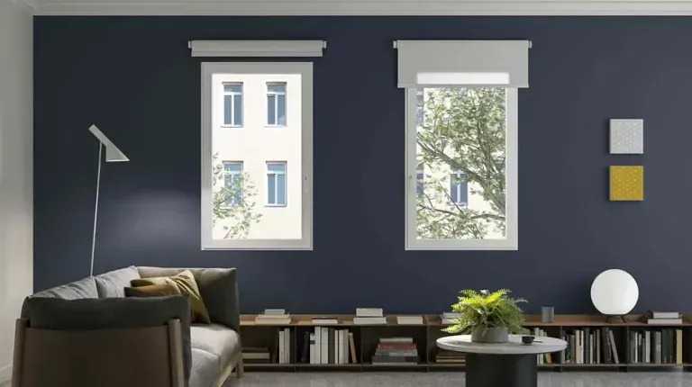 Soggiorno con parete blu navy, due finestre, divano, libreria integrata e arredamento minimalista.