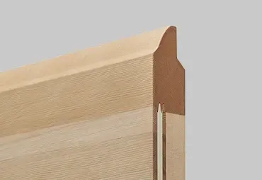 Primo piano dell'angolo di un telaio di una porta in legno, che mostra la modanatura decorativa e la scanalatura verticale.