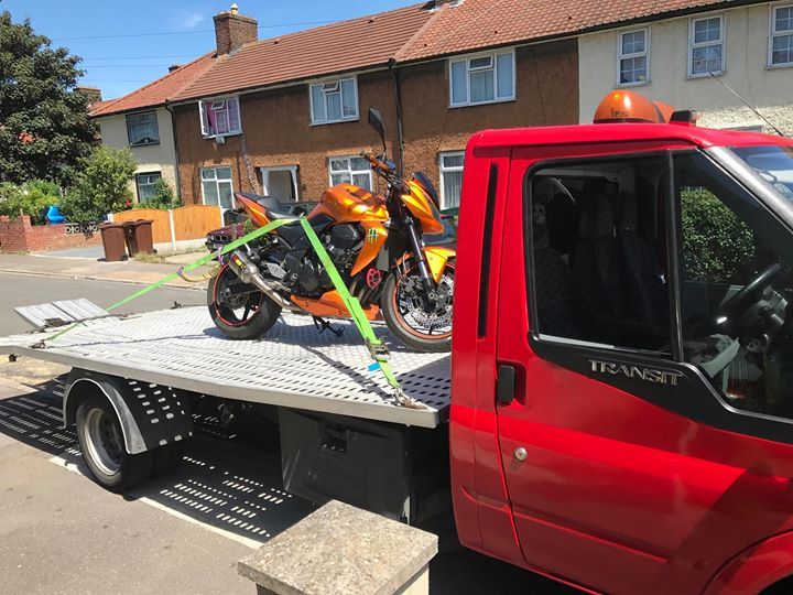A.C Recovery's, 24 hour towing service in Barking and Dagenham,  orange motorcycle being towed by red towing truck in  broad daylight