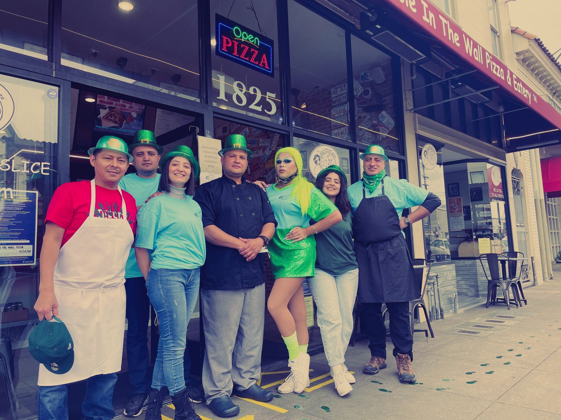 A group of people are posing for a picture in front of a pizza restaurant.