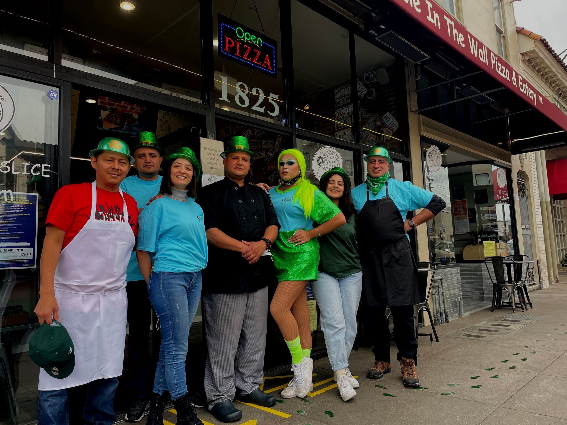 A group of people are posing for a picture in front of a pizza restaurant.