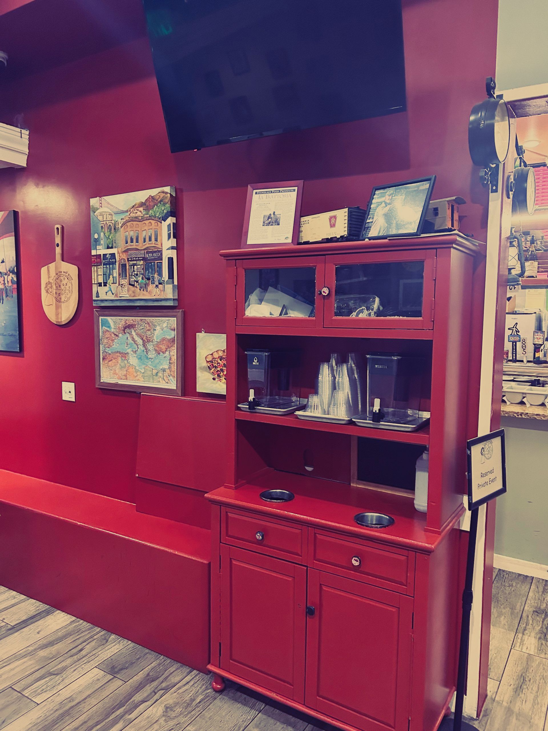 A red cabinet in a room with a tv on the wall.