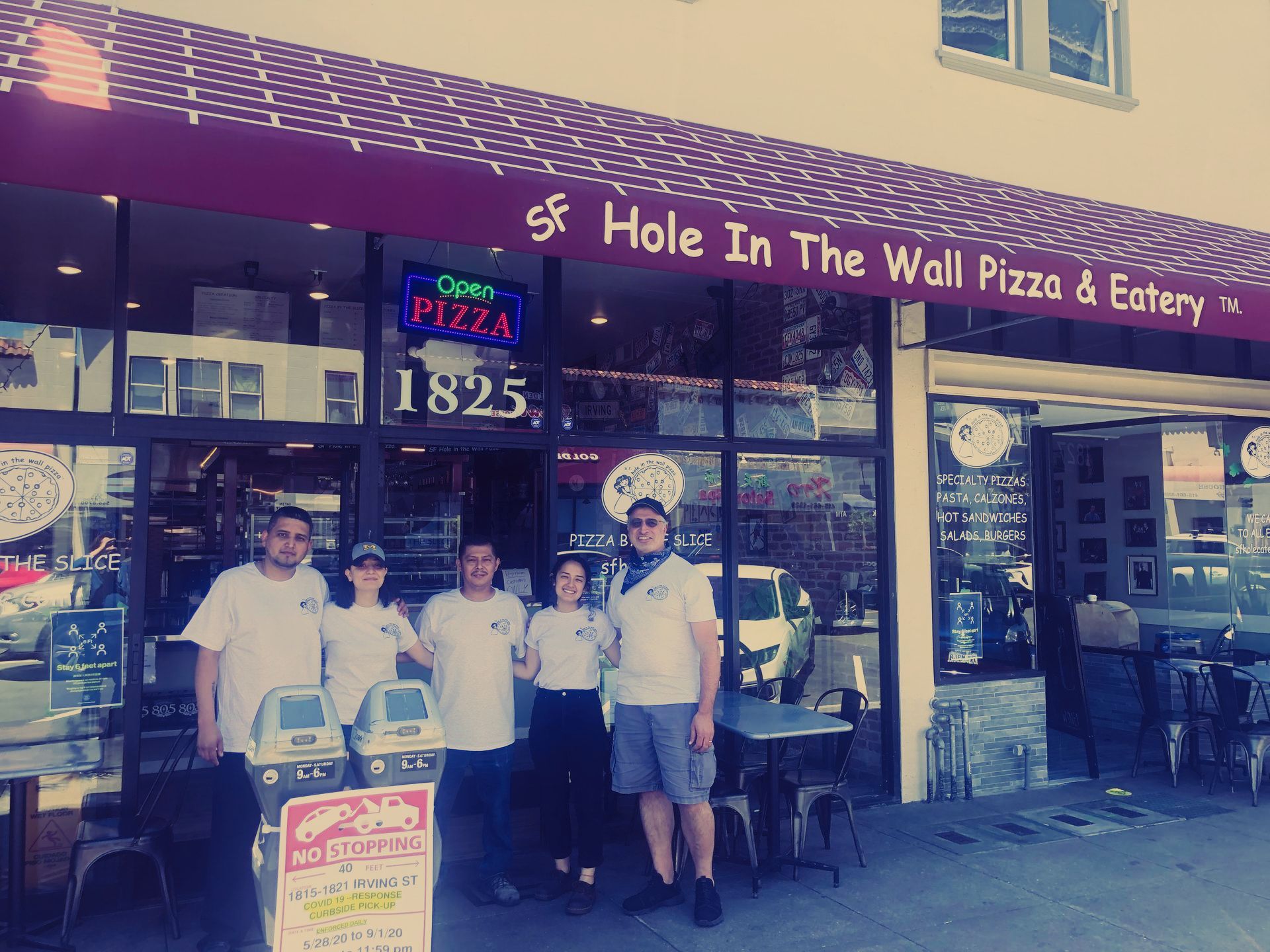 A group of people standing in front of a pizza restaurant.