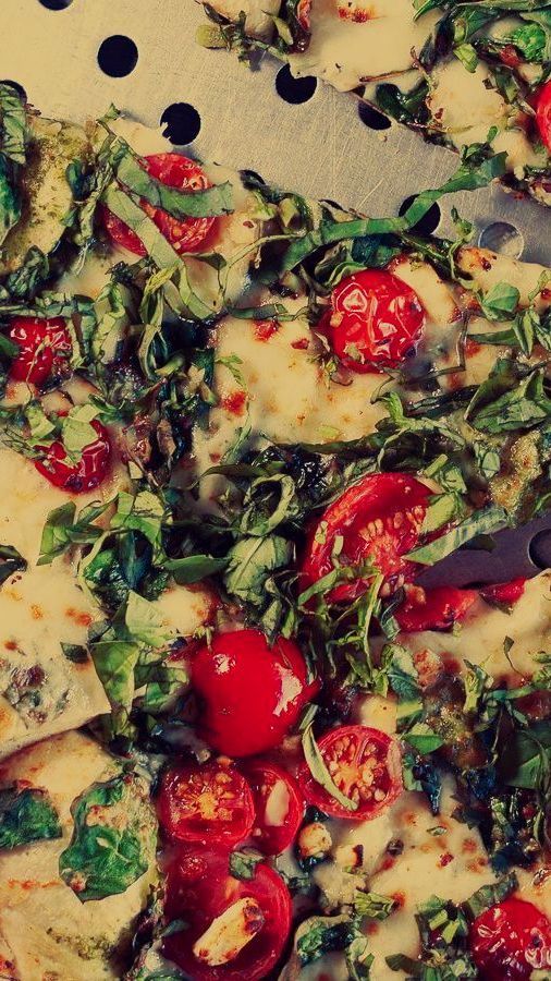 A pizza with tomatoes and spinach.
