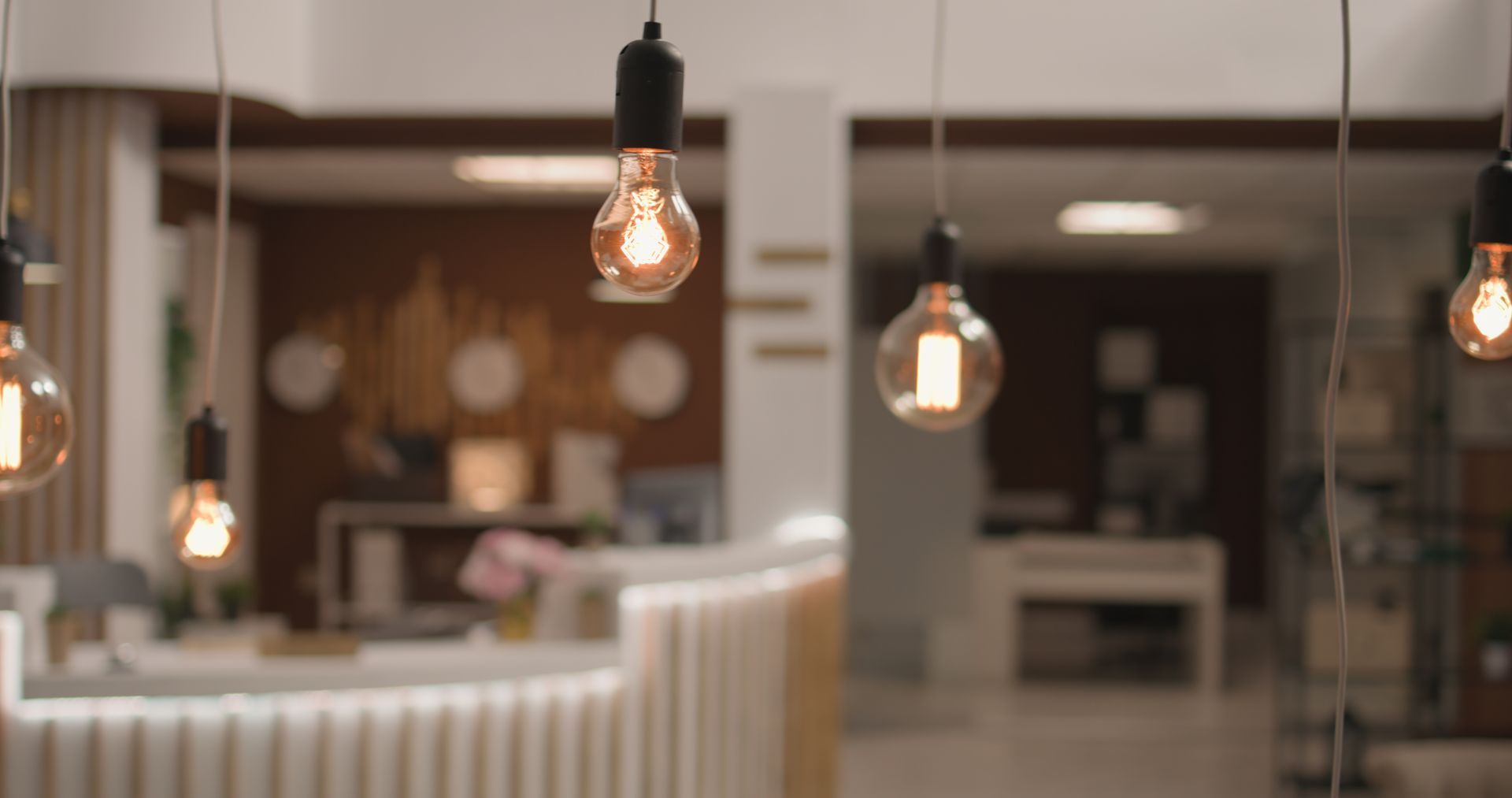 Decorative light bulbs hanging in a softly lit, modern office lobby.