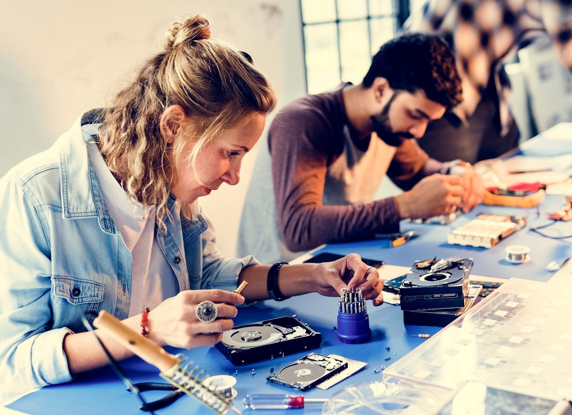 Trade school students learning electronics repair and technical skills in classroom lab.