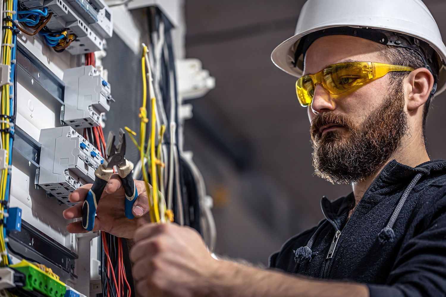 Male electrician working on switchboard, showcasing skilled electrical connections and practices.