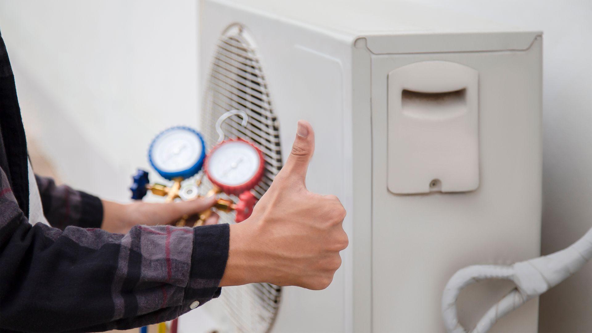 Hand giving a thumbs up next to a air conditioner.