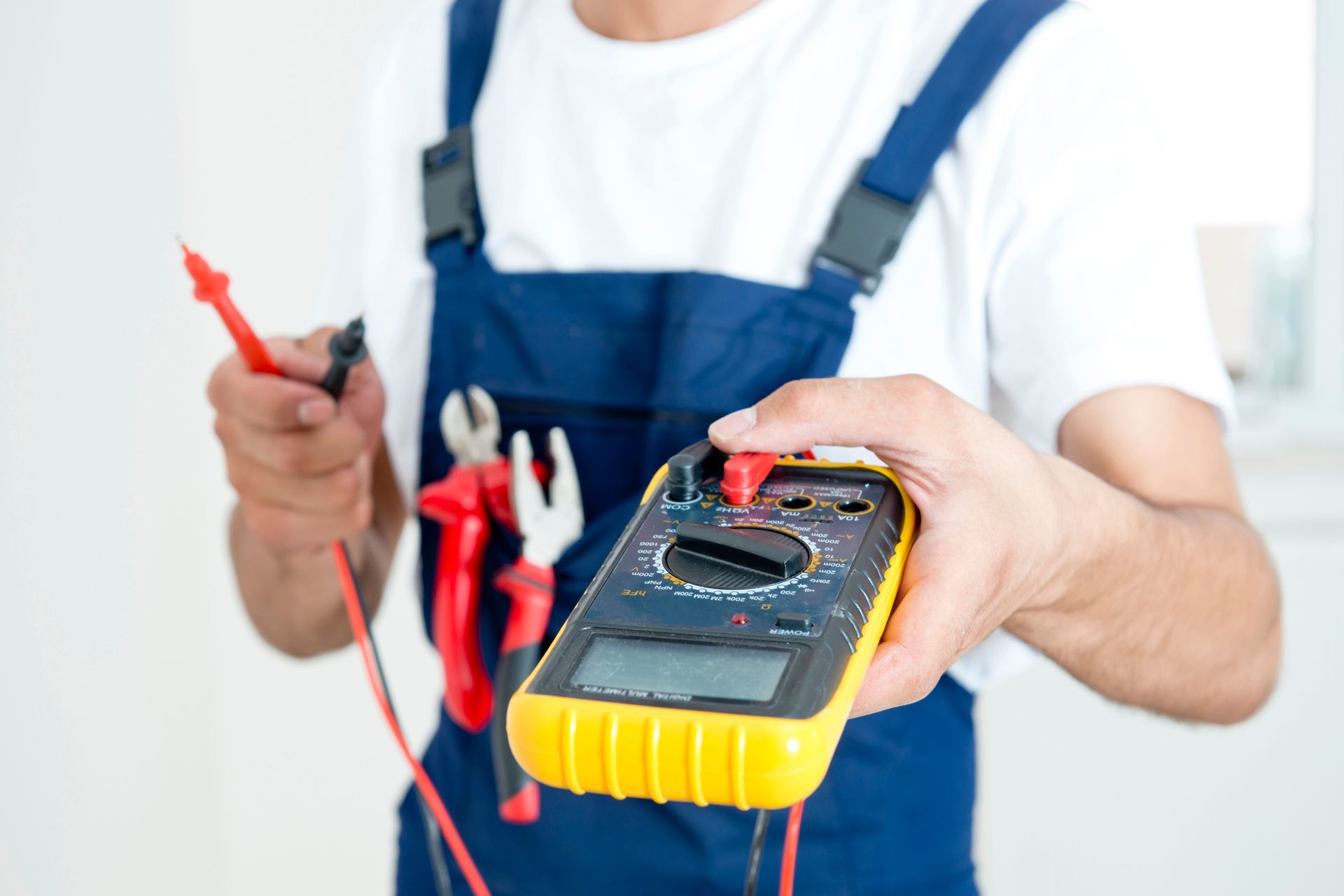 Electrician using multimeter during electrician training courses, holding tools and testing device. 