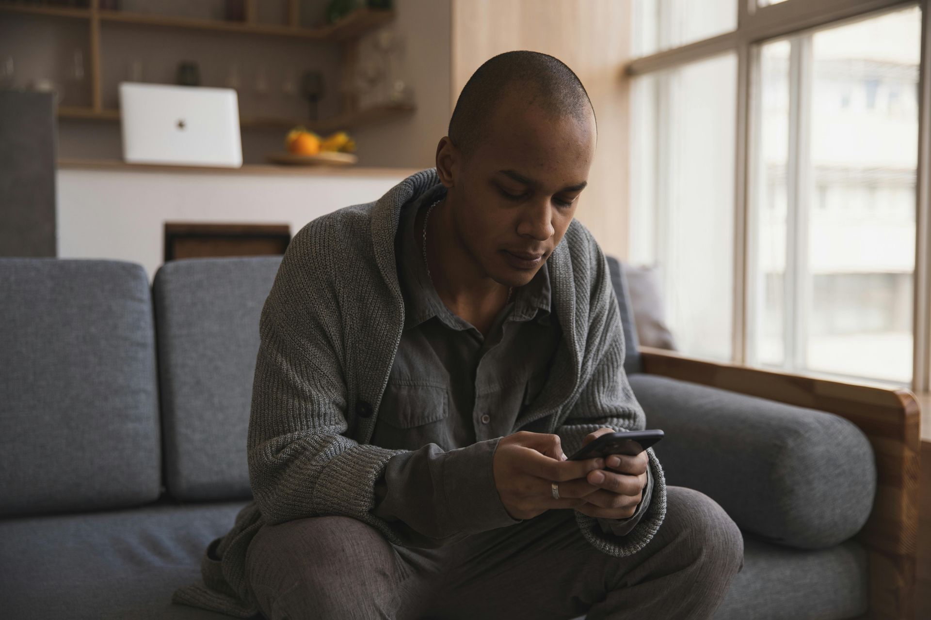 A man is sitting on a couch looking at his cell phone.