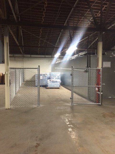 An empty warehouse with a chain link fence and a gate