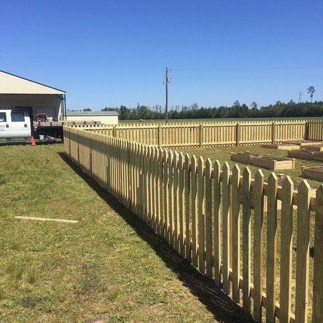 A wooden picket fence surrounds a lush green field