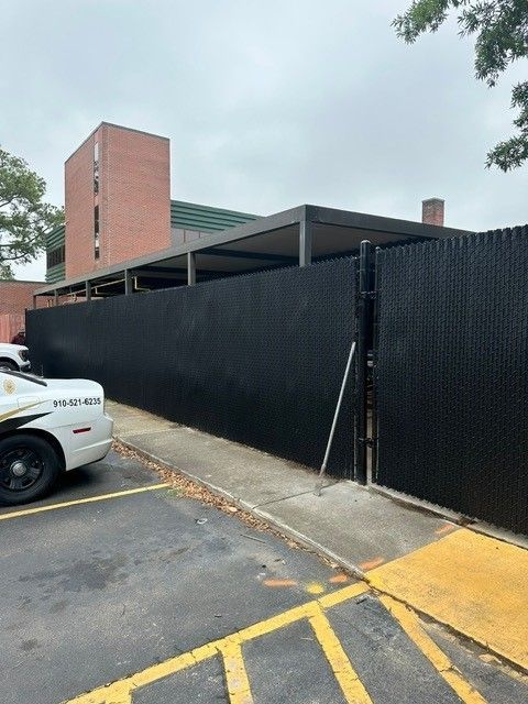 A police car is parked in front of a black fence.