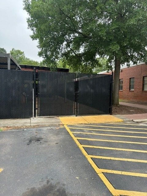 A parking lot with a fence and a tree in the background