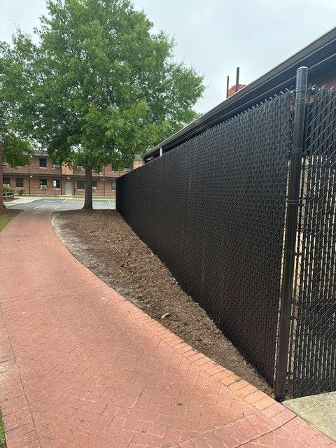 A black chain link fence along a brick sidewalk