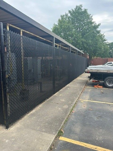 A chain link fence is surrounding a building in a parking lot.