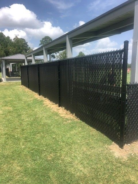 A black chain link fence is sitting on top of a lush green field.