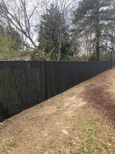 A long black chain link fence surrounds a dirt path.