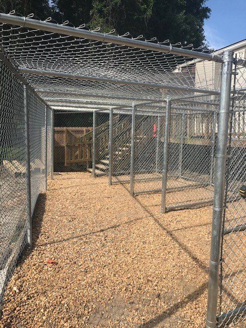 A chain link fence with stairs leading to a building behind it
