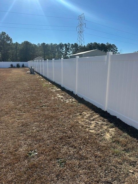 A white fence surrounds a dry grass field