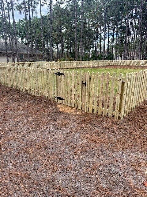 A wooden picket fence with a gate in the middle of a yard.