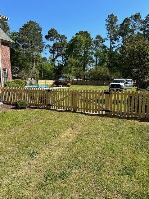 A wooden picket fence surrounds a lush green yard.