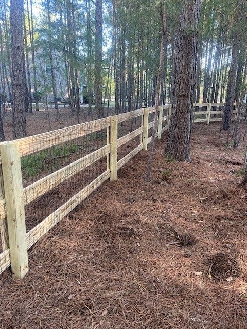 A wooden fence with a gate in the middle of a forest.