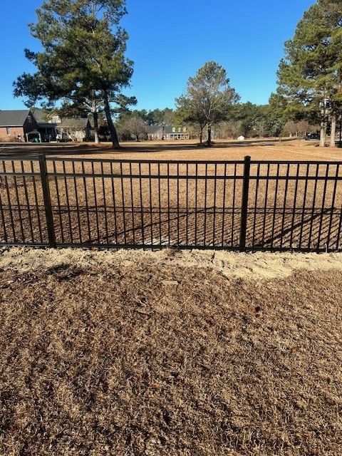 A fence surrounds a field with trees in the background
