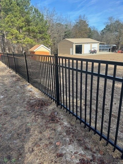 A black fence surrounds a yard with a garage in the background.