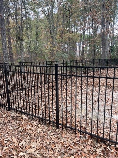 A black metal fence is surrounded by leaves and trees