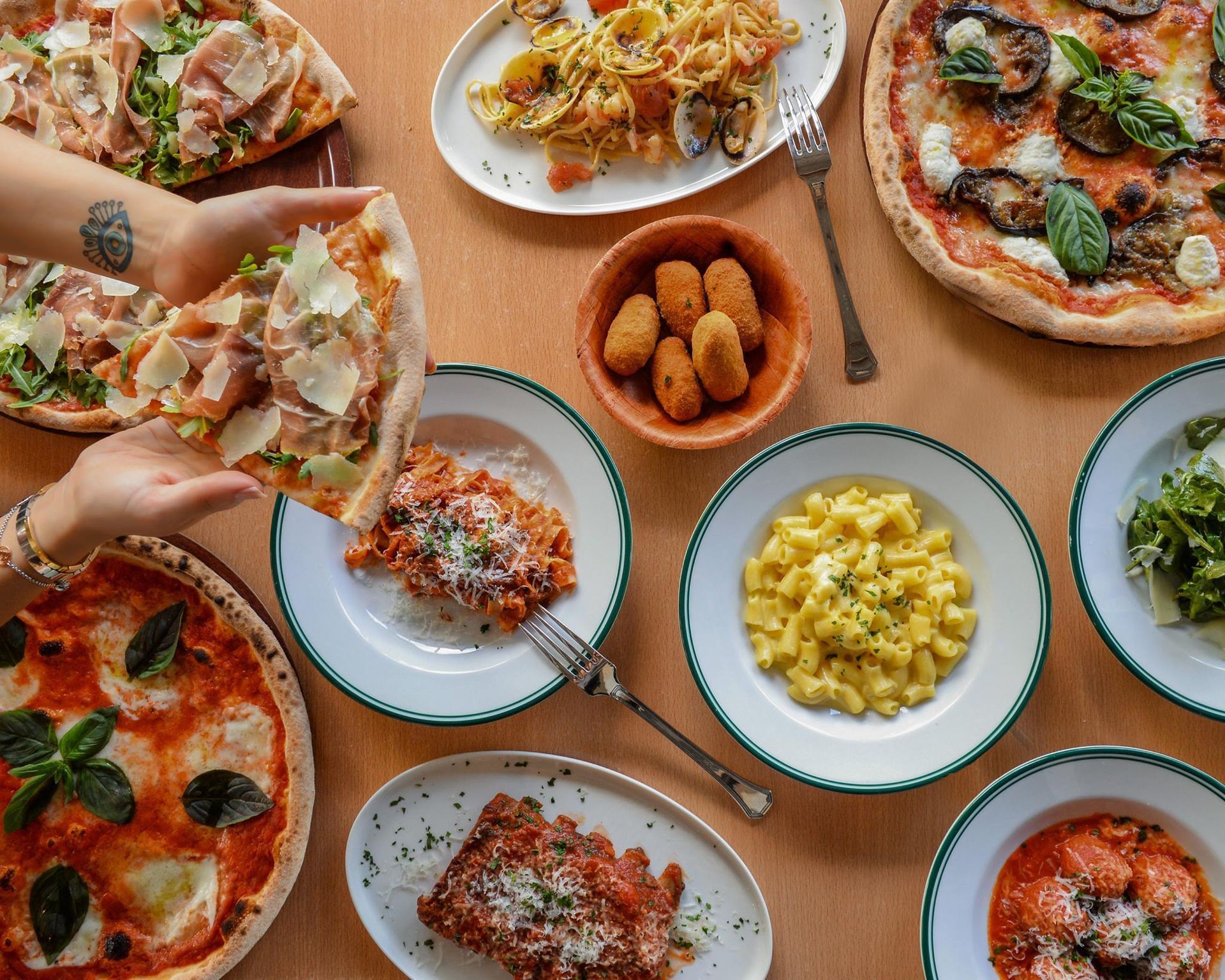 a person is holding a slice of pizza over a table full of food